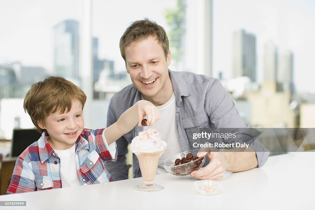 Père en regardant son fils mettre cerise sur Coupe glacée