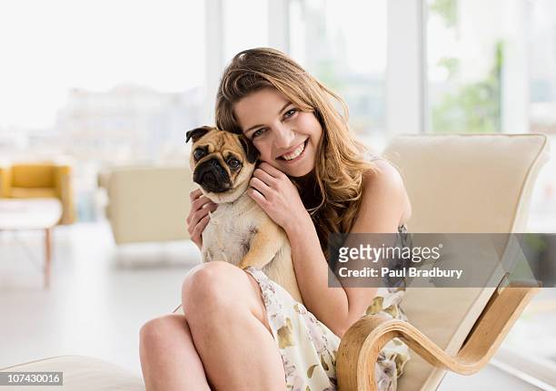 femme souriante tenant adorable petit chien sur les genoux - cute animals cuddling photos et images de collection