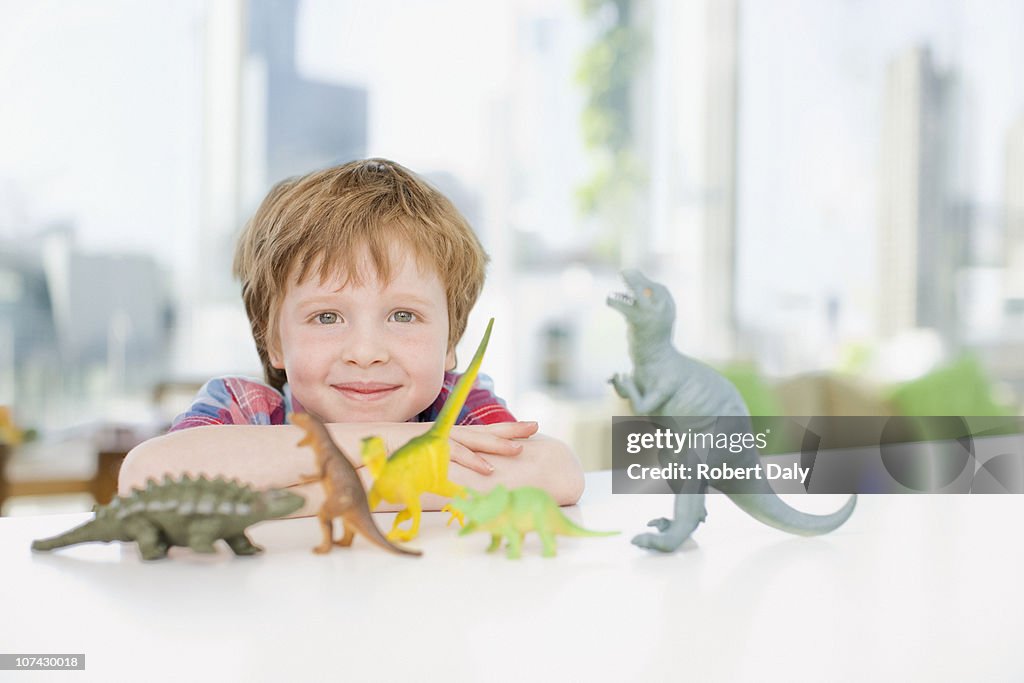 Sorridente Menino brincando com plástico dinossauros