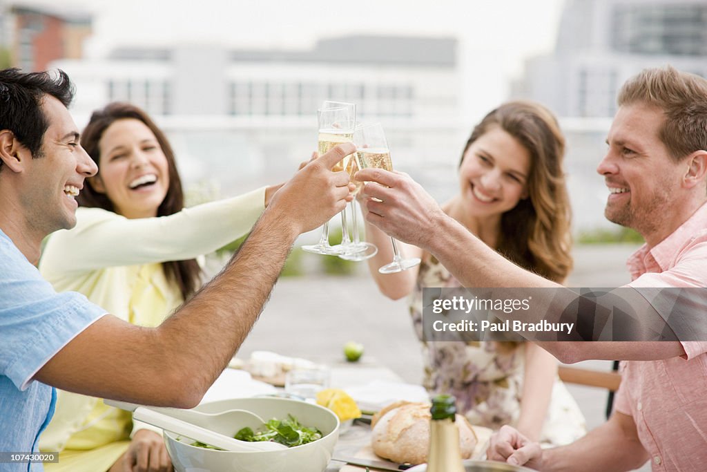 Laughing couples toasting with Champagne outdoors