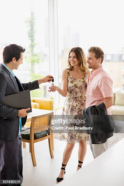 real estate agent handing couple keys to home - agent and handing keys stockfoto's en -beelden