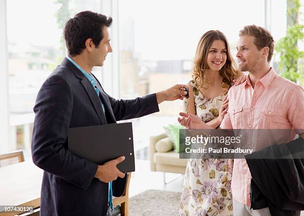 real estate agent handing couple keys to home - handing over keys stock pictures, royalty-free photos & images
