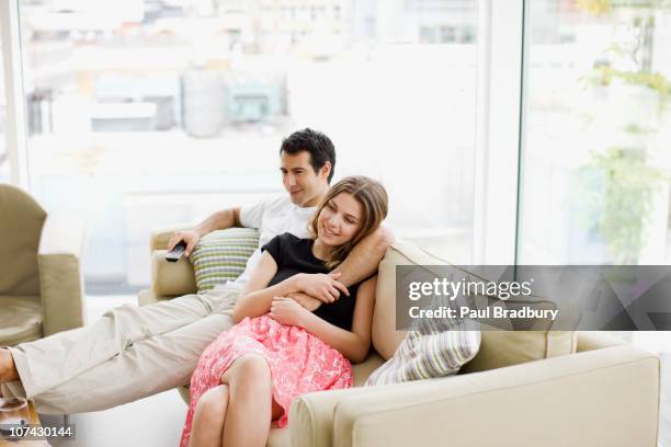 couple sitting on sofa watching television - women of penthouse stock pictures, royalty-free photos & images