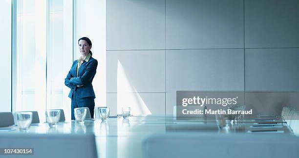 businesswoman standing alone in conference room - chief executive officer stock pictures, royalty-free photos & images