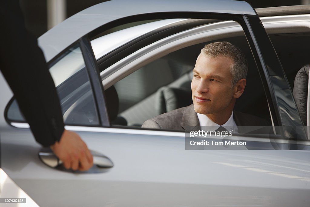Chauffeur opening car door for businessman