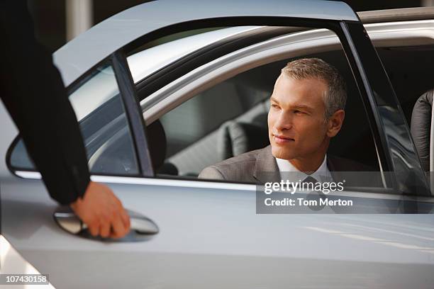 chauffeur opening car door for businessman - chauffeur 個照片及圖片檔