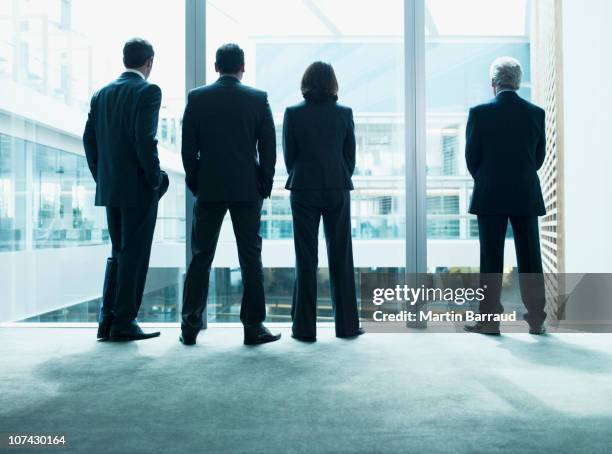 business people looking out glass wall together - group of businesspeople standing low angle view stock pictures, royalty-free photos & images