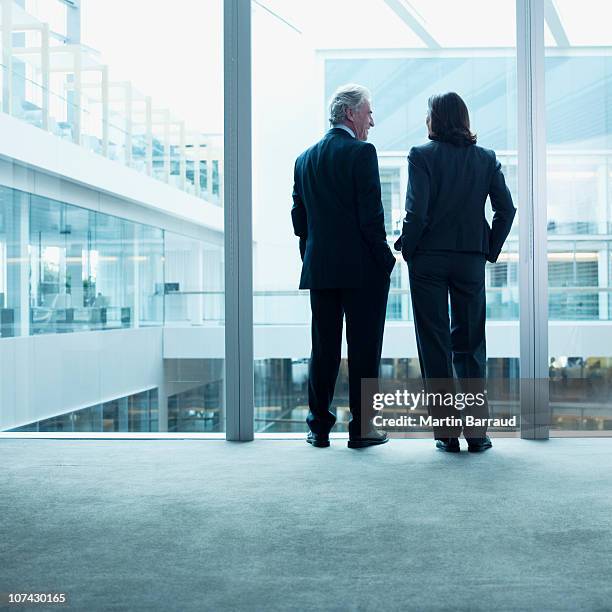 business people talking near glass wall in office - man standing talking stockfoto's en -beelden