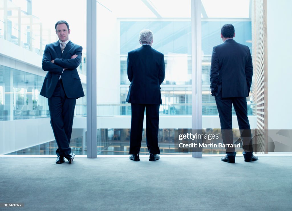 Businessmen standing near glass wall in office