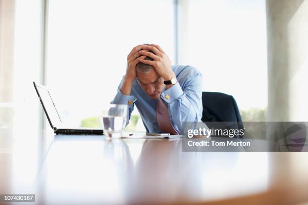 frustrated businessman with head in hands at desk - stressed businessman stock pictures, royalty-free photos & images