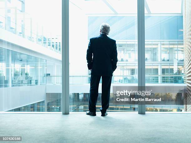 geschäftsmann schaut glaswand im büro - chief executive officer stock-fotos und bilder