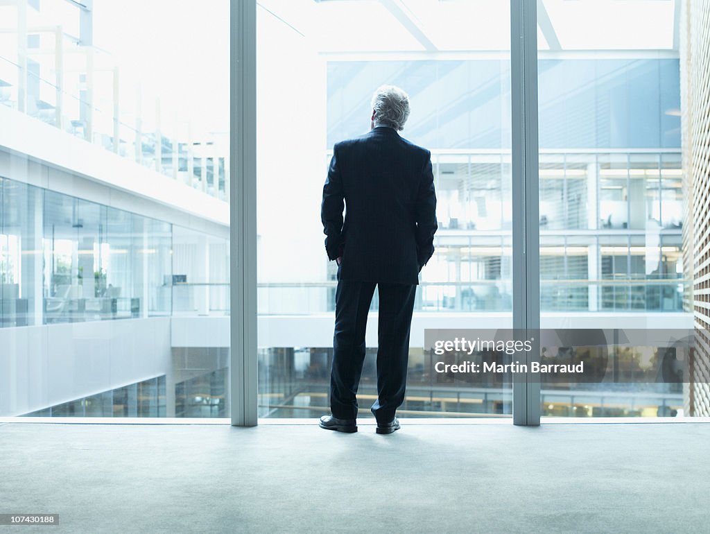 Businessman looking out glass wall in office