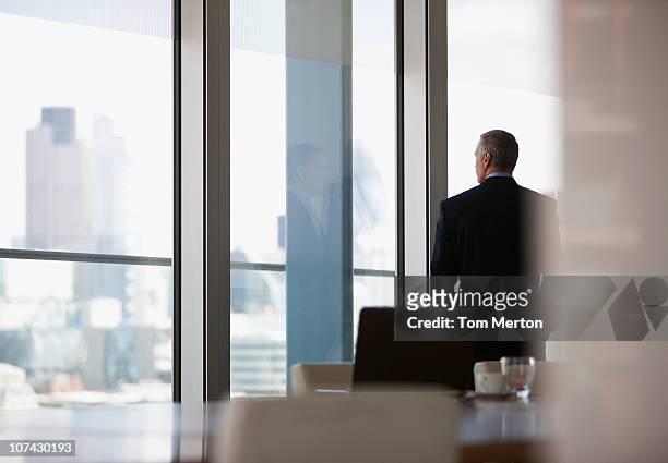 uomo d'affari guardando fuori la finestra sala conferenze - finestra foto e immagini stock