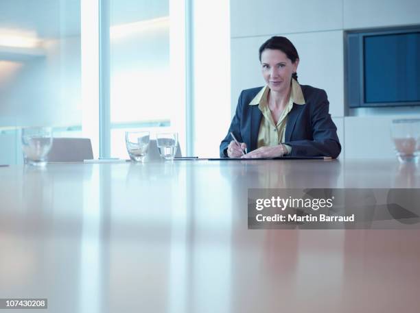 businesswoman working at office conference table - 50s woman writing at table stock pictures, royalty-free photos & images