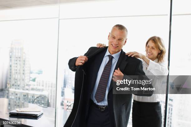 businesswoman helping co-worker put on coat - secretary stock pictures, royalty-free photos & images