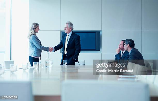 geschäftsleute schütteln die hände in konferenzraum - senior executives stock-fotos und bilder