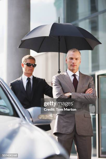 chauffeur holding umbrella for businessman - car sunshade stock pictures, royalty-free photos & images