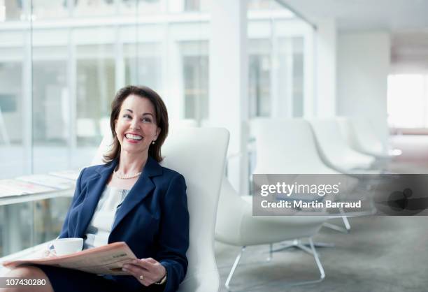 businesswoman reading newspaper in waiting area - hospitality lounge at the longines global champions tour of london stockfoto's en -beelden