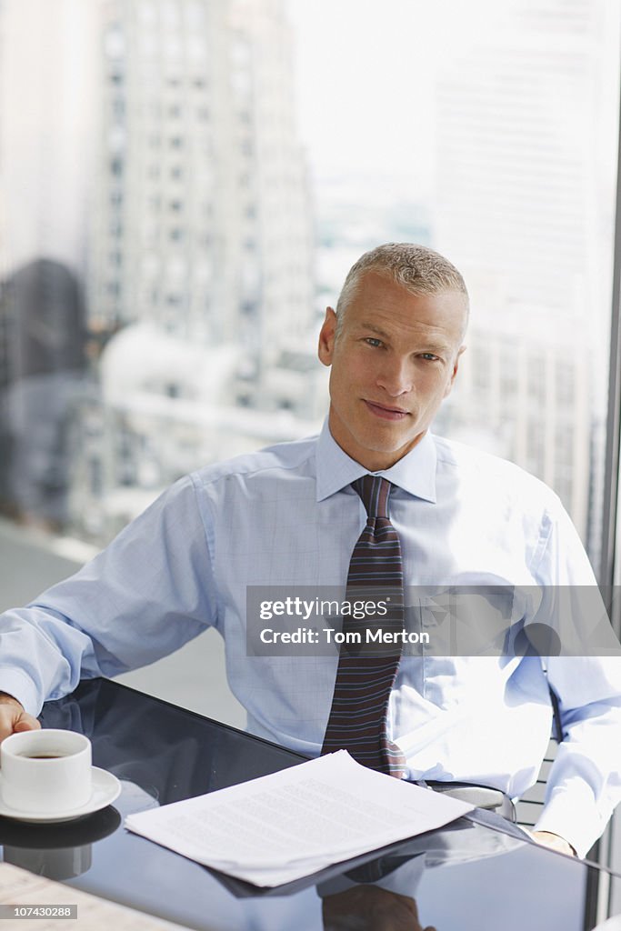 Businessman sitting at desk drinking coffee
