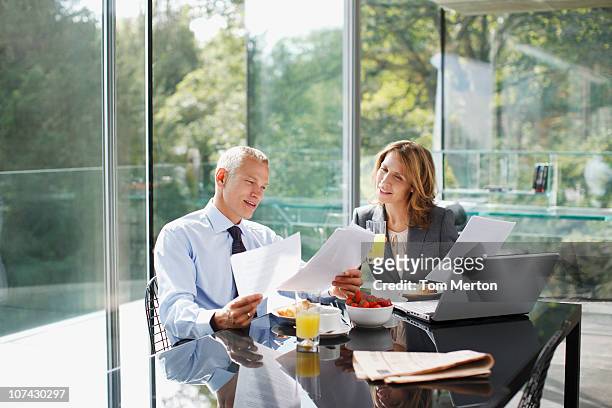 business people working over breakfast - 40s couple sunny stock pictures, royalty-free photos & images