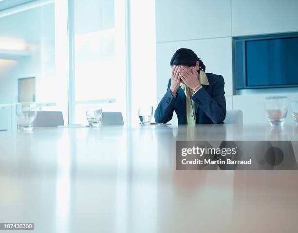 frustrated ビジネスウーマンのコンファレンステーブルに座る - 手を顔にやる ストックフォトと画像