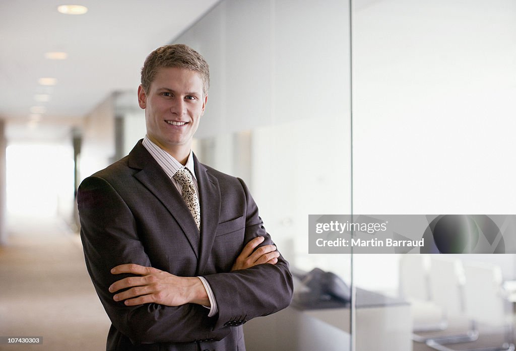 Businessman with arms crossed in office corridor
