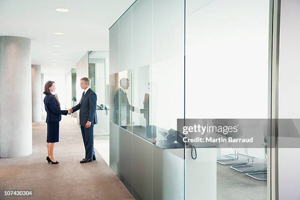 business people shaking hands in modern office corridor - businessman and businesswoman shaking hands stock pictures, royalty-free photos & images