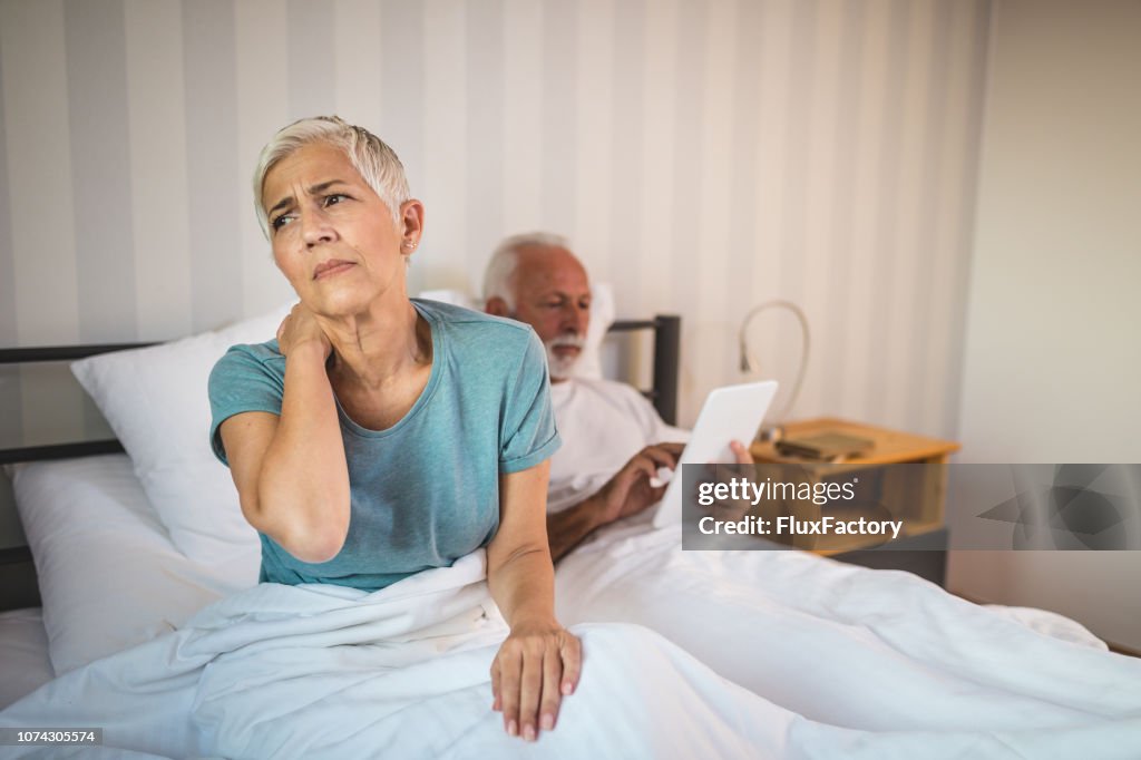 Senior wife in bed having a neckache