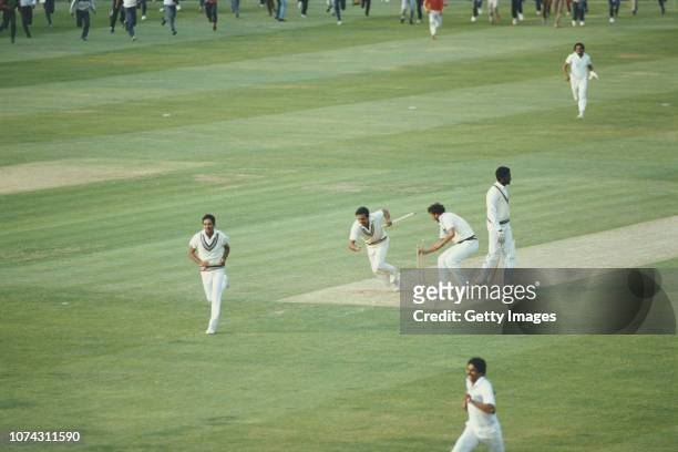 Victorious India players Yaspal Sharma and Roger Binny grab souvinir stumps as Mohinder Amarnath runs off the field as West Indies batsman Michael...