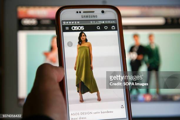 In this photo illustration, a woman is seen shopping on ASOS the online fashion store on a mobile phone. Shares in Asos tumbled nearly 40 per cent on...