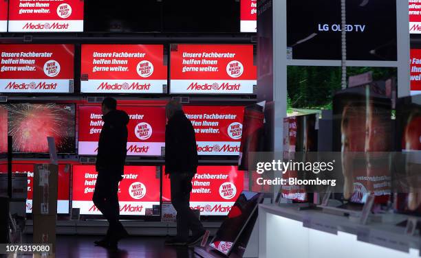 Customers browse flat screen televisions inside a Media Markt electronic goods store, operated by Ceconomy AG, in Berlin, Germany, on Monday, Dec....