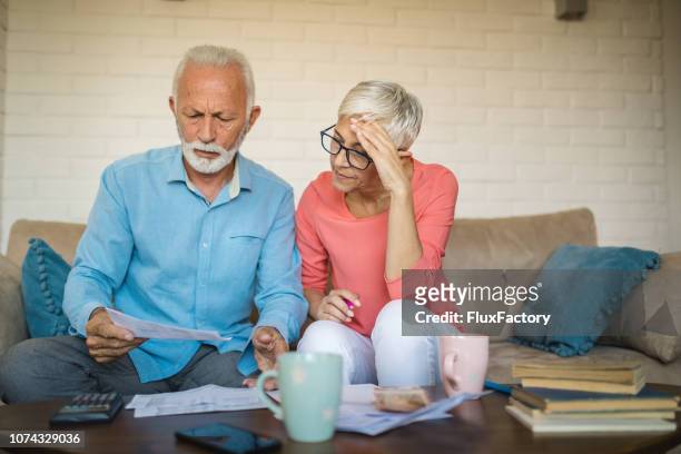 älteres paar brainstorming-die lösung für ein finanzielles problem - grumpy old man stock-fotos und bilder