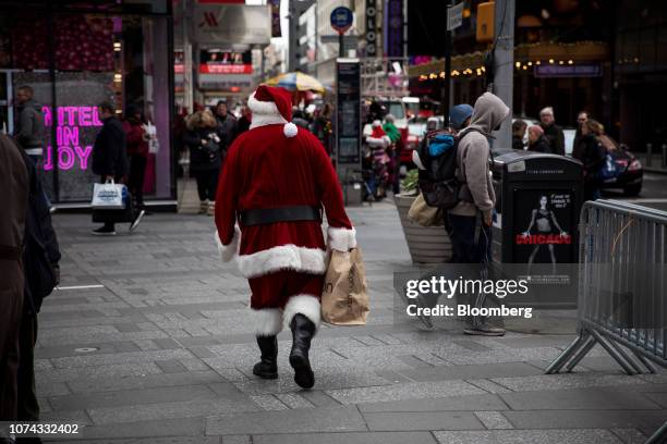 Person dressed in a Santa Claus costume carries a Bloomingdale's Inc. Shopping bag in the Times Square neighborhood of New York, U.S., on Monday,...