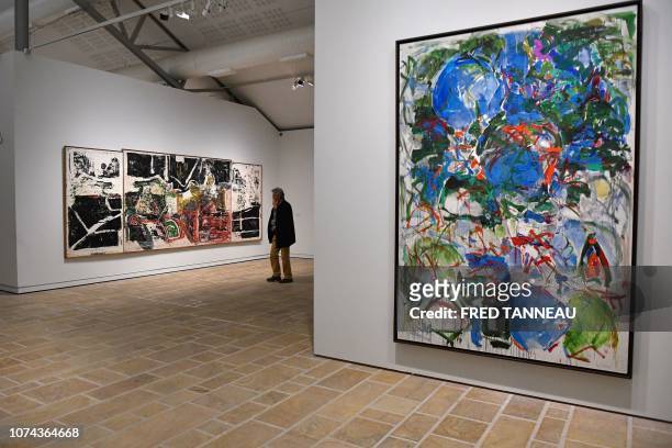 Man looks at an oil painting "De la grande baleine" by Canadian Jean-Paul Riopelle next to an oil painting "Mon paysage" by US Joan Mitchell during...