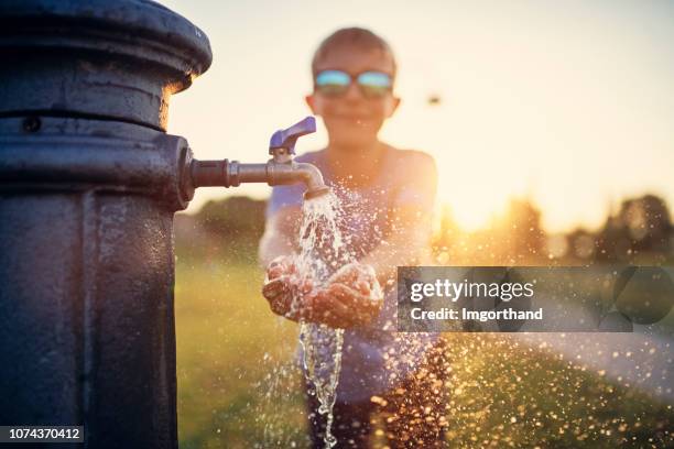 little boy drinking water from public fountain - faucet stock pictures, royalty-free photos & images