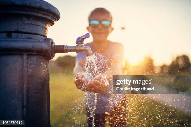 little boy drinking water from public fountain - drinking water outside stock pictures, royalty-free photos & images