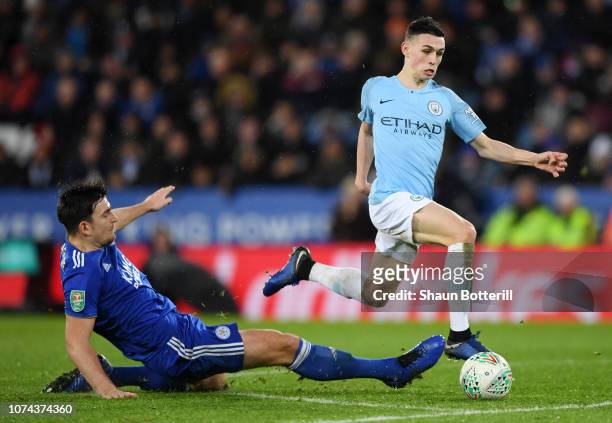 Phil Foden of Manchester City is challenged by Harry Maguire of Leicester City during the Carabao Cup Quarter Final match between Leicester City and...