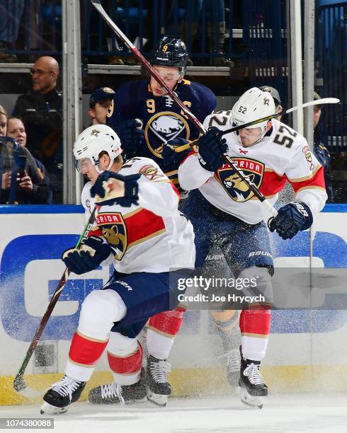 Jack Eichel of the Buffalo Sabres is checked against the boards by MacKenzie Weegar and Mark Pysyk of the Florida Panthers during an NHL game on...