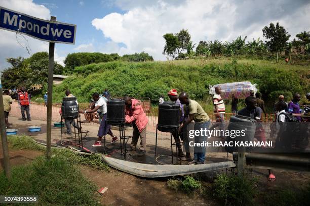People from Democratic Republic of Congo wash their hands at the Ebola screening point bordering with DRC in Mpondwe, western Uganda, on December 12,...