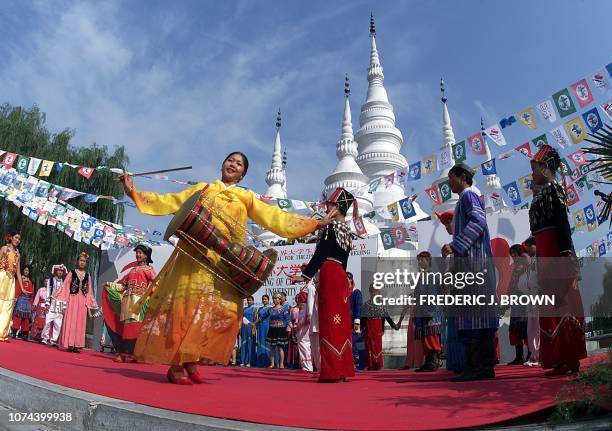 Performers representing China's ethnic-minority groups dance on stage in front of a pagoda from southwestern China's Yunnan province, representing...