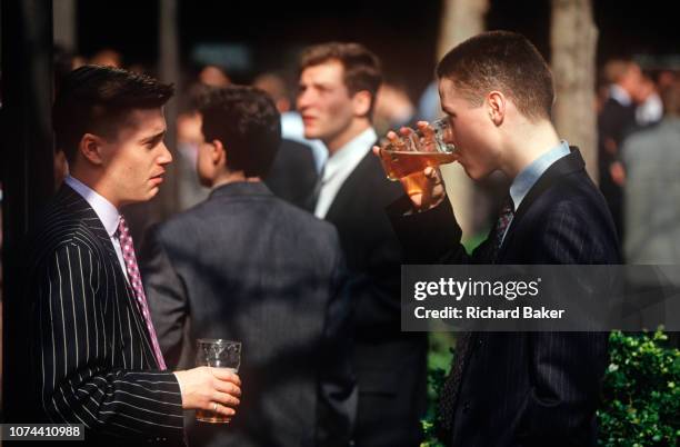 Two young 1990s city workers drink pints of beer outside a pub in the City of London , the capital's financial centre, on 20th May 1993, in London,...