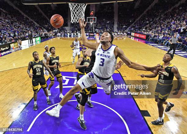Kamau Stokes of the Kansas State Wildcats gets fouled from behind, driving to the basket against the Southern Miss Golden Eagles during the first...