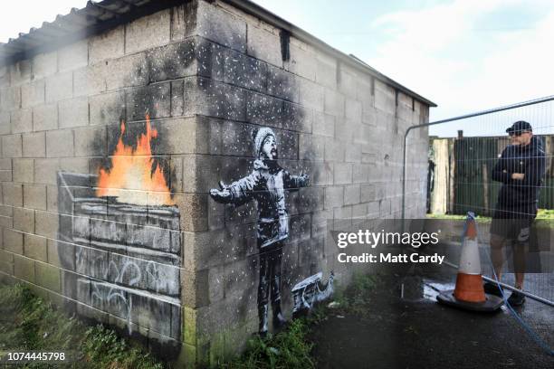 People gather around fences that have been erected to protect the latest piece of artwork by the underground guerrilla artist Banksy on December 20,...