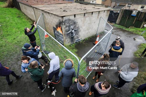 People gather around fences that have been erected to protect the latest piece of artwork by the underground guerrilla artist Banksy that has...