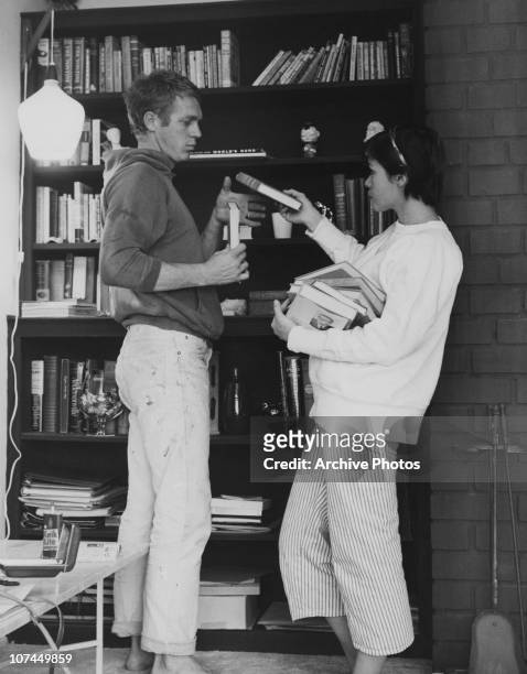 American actor Steve McQueen help his first wife, actress Neile Adams, stack books on a bookshelf, circa 1958.