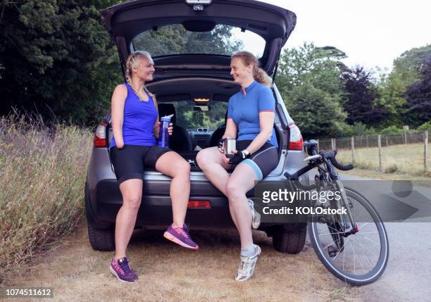 Two woman cyclist sitting down drinking