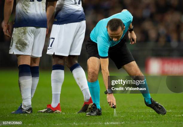 Referee Cuneyt Cakir marks the defensive wall position with aerosol spray during the Group B match of the UEFA Champions League between Tottenham...