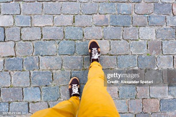 walking on the cobbled street in sneakers, personal perspective high angle view - un escalón fotografías e imágenes de stock