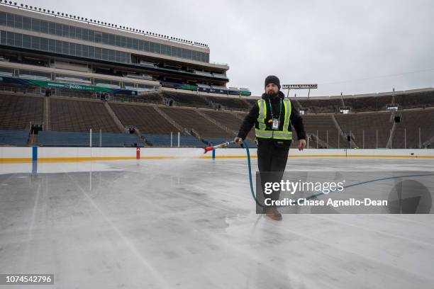 Members of the NHL ice crew spray water as they build the ice rink at Notre Dame Stadium on December 21, 2018 in South Bend, Indiana in preparation...