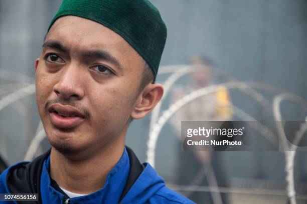 Jakarta, Indonesia, 21 December 2018 : A demonstrant cried with barbwire and a policeman in the background during the demonstration as his feeling to...